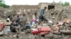 People collect their belongings from damaged homes after heavy flooding in the Khushi district of Logar Province on August 21.