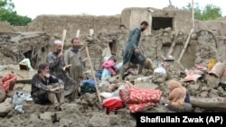 People collect their belongings from damaged homes after heavy flooding in the Khushi district of Logar Province on August 21.