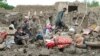 An Afghan family looks at their house, which was destroyed by heavy flooding in the east of the country. 