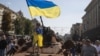 A boy waves a Ukrainian flag on top of an armored personal carrier at an exhibition of destroyed Russian military vehicles and weapons in the center of Kyiv dedicated to the country's upcoming Independence Day on August 24. 