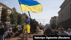 A boy waves a Ukrainian flag on top of an armored personal carrier at an exhibition of destroyed Russian military vehicles and weapons in the center of Kyiv dedicated to the country's upcoming Independence Day on August 24. 