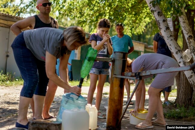 Banorët mblidhen për të nxjerrë ujë nga një pus jashtë një kompleksi apartamentesh në Sloviansk, rajoni Donjeckut, në Ukrainën lindore, 6 gusht 2022.