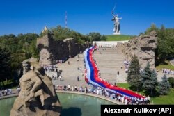 Люди несут гигантский российский флаг на Мамаевом кургане, мемориале Сталинградской битвы, 22 августа 2022 года