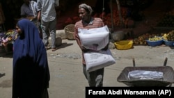 Човек од Сомалија носи вреќа пченично брашно од Турција
