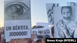 Disa persona shihen duke mbajtur mbishkrime në duar në sheshin e Tiranës, gjatë protestave pasi u bë publik rasti i dhunimit të një 11-vjeçareje në Prishtinë nga pesë të dyshuar. 31 gusht 2022. 
