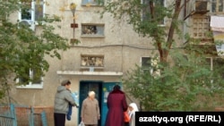 Жители дома № 4 в микрорайоне Авангард стоят перед входом в подъезд, в котором жил атырауский смертник Бауржан Султангалиев. Атырау, 3 ноября 2011 года.
