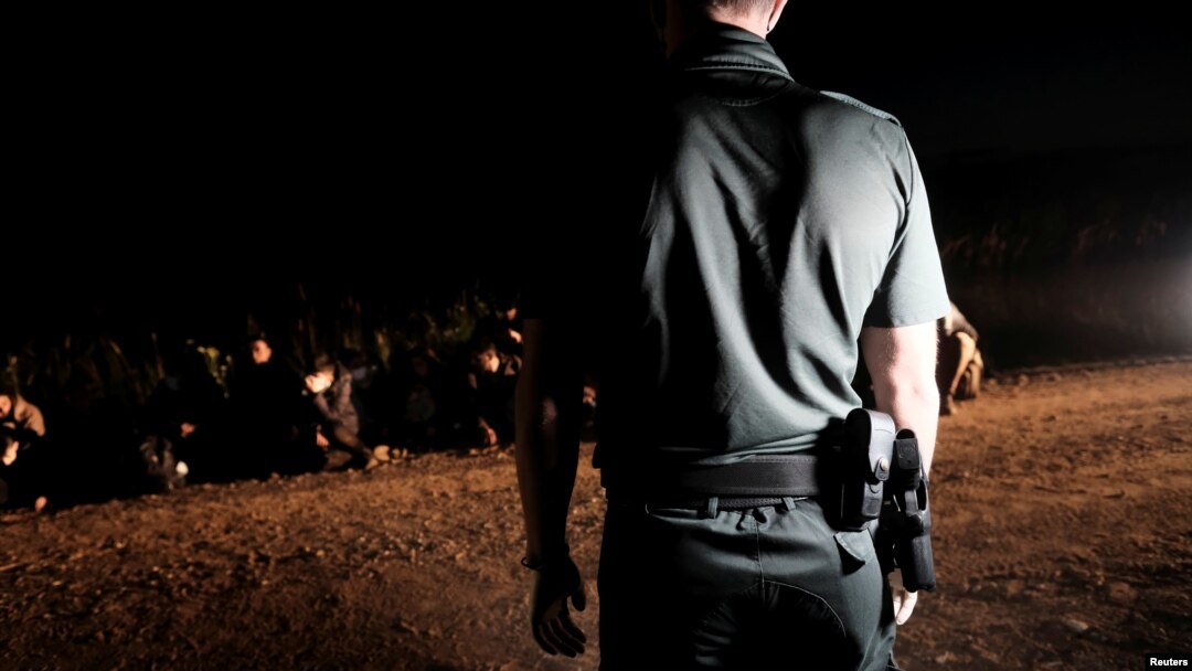 Latvian border guard with detained migrants on the Belarus-Latvia border.