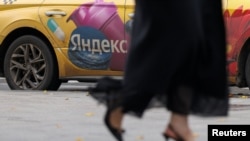 A woman walks past a Yandex-branded taxi in Moscow. (file photo)