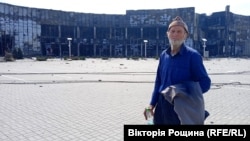 85-річний мешканець Маріуполя Сергій на тлі розбомбленого ТЦ «Порт Сіті» в Маріуполі. Чоловікові дивом вдалося вибратися з квартири, в яку влучив снаряд. Квітень 2022 року