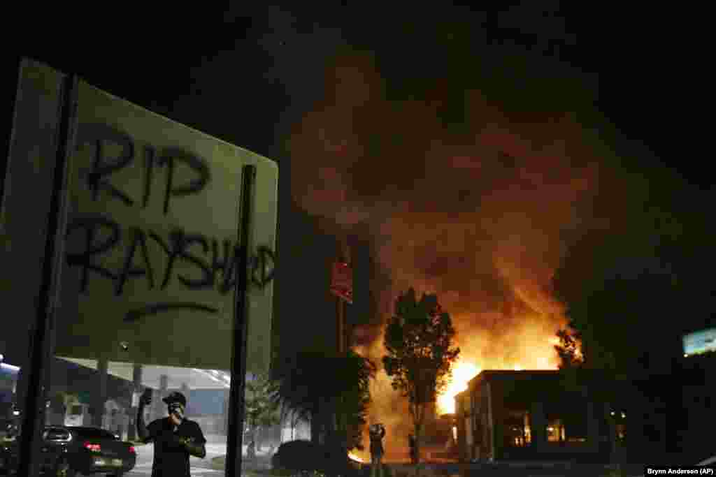 &quot;RIP Rayshard&quot; is spray painted on a sign as as flames engulf a Wendy&#39;s restaurant during protests Saturday, June 13, 2020, in Atlanta. The restaurant was where Rayshard Brooks was shot and killed by police Friday evening following a struggle in the restaurant&#39;s drive-thru line. The &nbsp;restaurant was later set on fire by protesters.