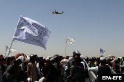 A helicopter flies over supporters of the Taliban as they gather in Kandahar on September 1, 2021.