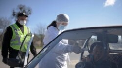 A medical worker checks the temperature of a passenger at a checkpoint outside the city of Lviv.