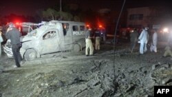 Pakistani policemen examine the site of a bomb attack targeting a senior police officer in Karachi, September 25, 2014.