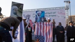  Iraq Protests Protesters burn Israeli and US flags while others carry posters with pictures of Qais al-Khazali, during a rally for the Shiite group Asaib Ahl al-Haq, in Baghdad, Iraq, Saturday, Dec. 14, 2019. (AP Photo/Nasser Nasser)