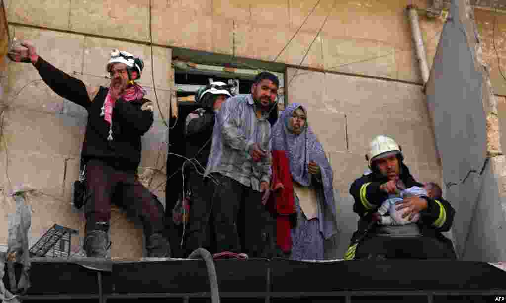 Syrian civil defense volunteers evacuate a family from a damaged building following a reported air strike on April 24 in the rebel-held neighborhood of Tareeq al-Bab in the northern city of Aleppo. (AFP/Ameer Alhalbi)