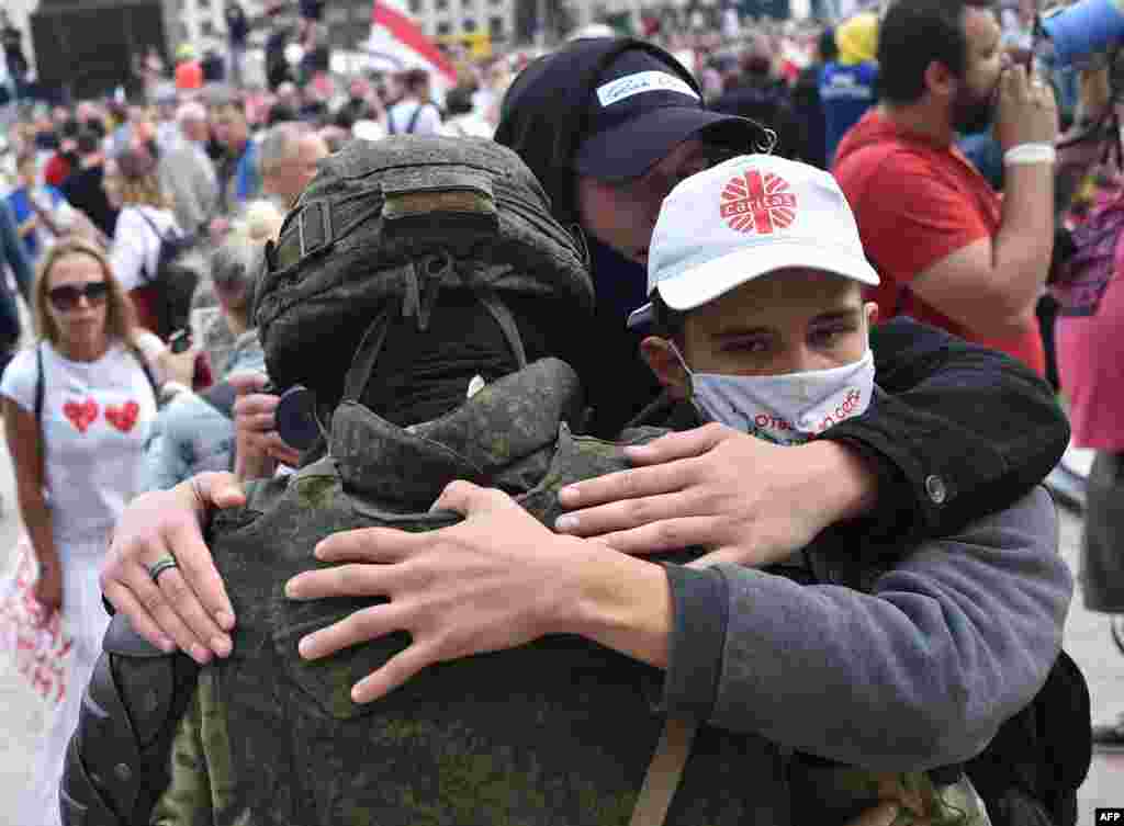 People hug a Belarusian law enforcement officer during a protest rally against police violence during recent rallies against the results of the presidential election in central Minsk on August 14. (AFP/Sergei Gapon)