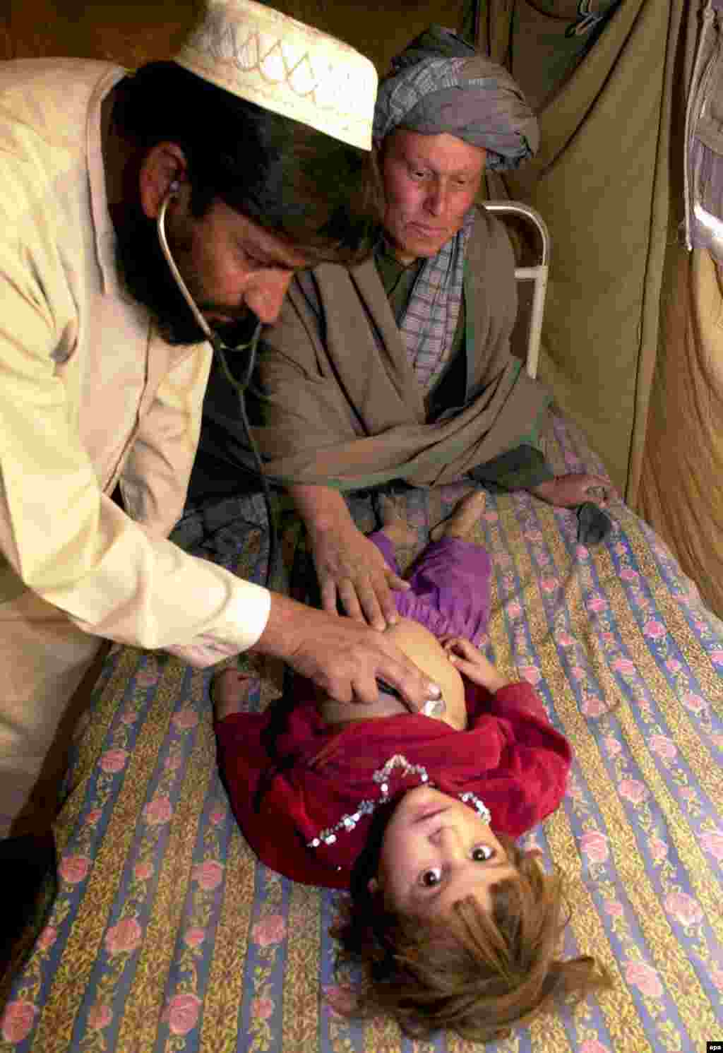 A doctor attends to a sick child who is among the displaced persons in the Afghan border town of Spin Boldak - In 2001, the UN said that more than 3 million Afghan refugees were either in camps (1.2 million) or cities and towns (2 million) throughout Pakistan.