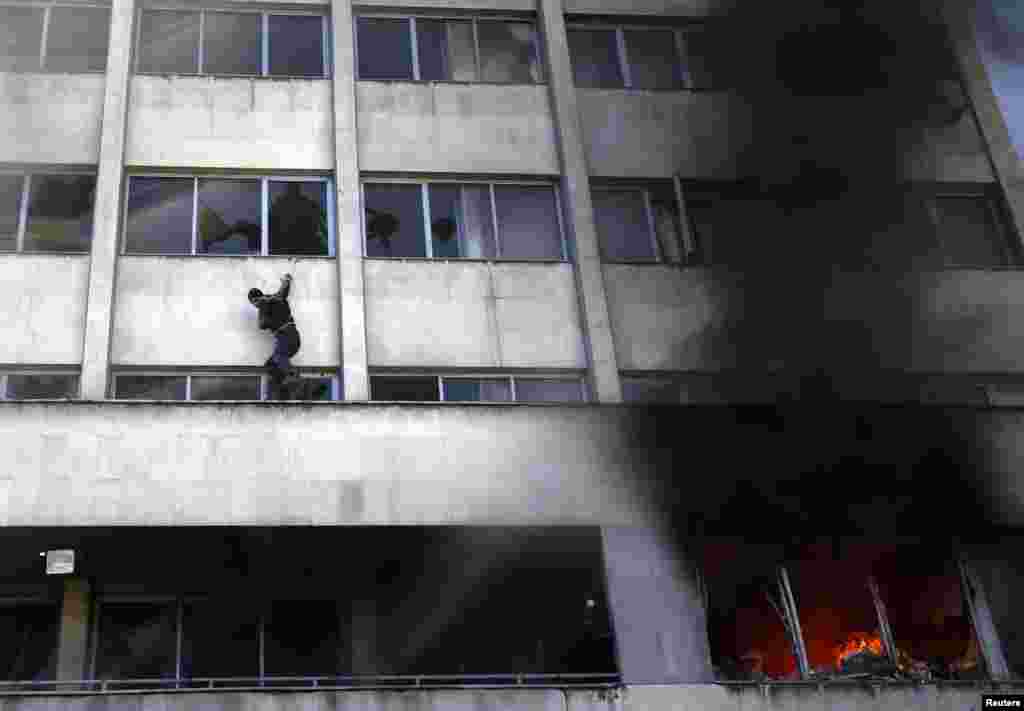 Një njeri duke ikur nga flaka që kishte kapluar një ndërtesë qeveritare në Tuzla të Bosnje-Hercegovinës, më 7 shkurt. Protestuesit kishin vënë zjarrin ndërtesës gjatë protestave të dhunshme me policinë, për shkak të papunësisë së lartë dhe inercionit politik. (Dado Ruvic, Reuters)