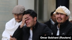 Afghan men cry at a hospital after they heard that their relative was killed during an attack in Kabul on March 6