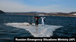 Two fishermen use a smaller piece of ice as a raft and try to row to land in Mordvinov Bay off Sakhalin Island on January 28.