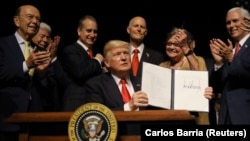 АҚШ президенті Дональд Трамп (ортада) Кубамен қатынас туралы құжатқа қол қойғаннан кейін оны көрсетіп отыр. Майами, Флорида, 16 маусым 2017 жыл.