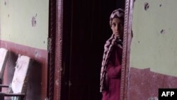 A Pakistani Kashmiri girl stands alongside a bullet-riddled wall of her house following the cross-border shelling in the village of Peer Klanjer, on the Nakyal sector in November.