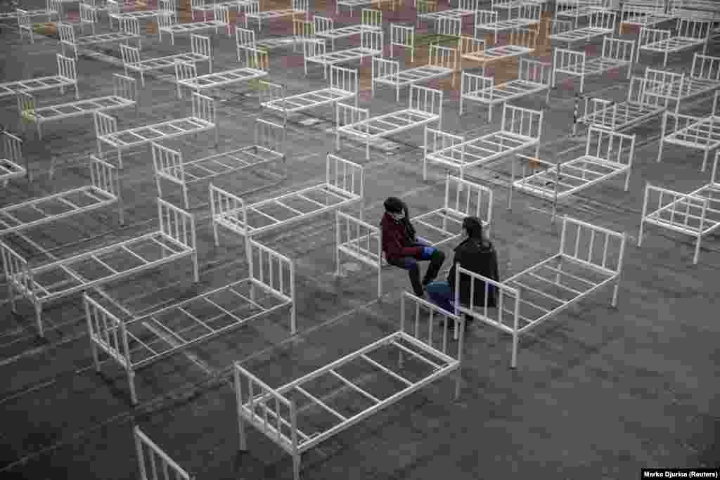 Volunteers take a break as they set up beds inside the Novi Sad Fair to accommodate people who suffer mild symptoms of the coronavirus in Novi Sad, Serbia, March 27.