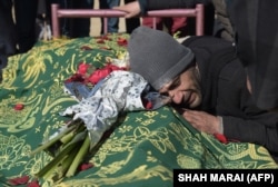 A relative mourns alongside the body of Saeed Jawad Hossini, 29, who was killed in the suicide attack on the Tolo TV minibus in January 2016.