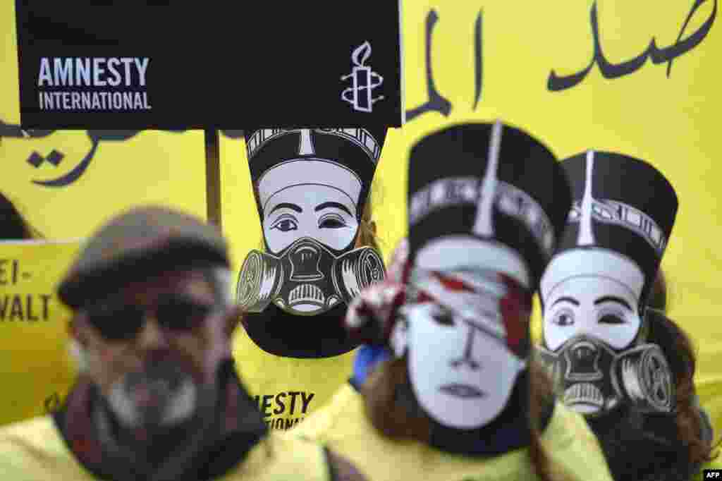 Activists supporting the human rights watchdog Amnesty International wear masks featuring Egypt's Queen Nefertiti wearing a gas mask as they demonstrate near the Chancellery where Germany's chancellor was to meet with Egypt's president in Berlin. (AFP/Odd Andersen)