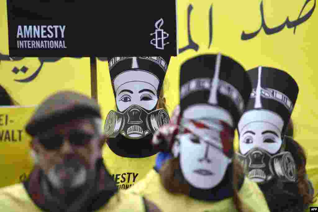 Activists supporting the human rights watchdog Amnesty International wear masks featuring Egypt&#39;s Queen Nefertiti wearing a gas mask as they demonstrate near the Chancellery where Germany&#39;s chancellor was to meet with Egypt&#39;s president in Berlin. (AFP/Odd Andersen)