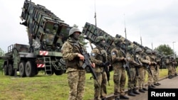 Militari germani aliniați în spatele unor baterii Patriot, în timpul unei vizite a președintelui ucrainean Volodimir Zelenski la un poligon din Germania, în 2024. Ucraina are nevoie de sistemele americane de apărare antiaeriană pentru a-și proteja orașele de atacurile rusești. 