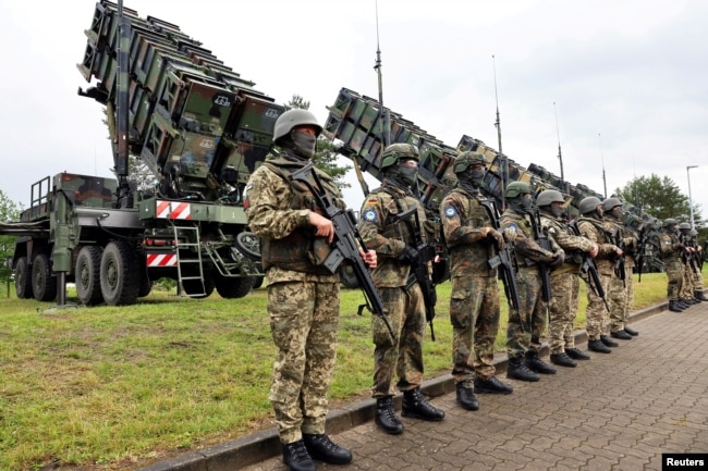 Soldați în așteptarea președintelui Zelenski la o bază din Germania, în iunie 2024. Bateriile Patriot, din spatele lor, fabricate în SUA, sunt dorite de Kiev în număr cât mai mare.