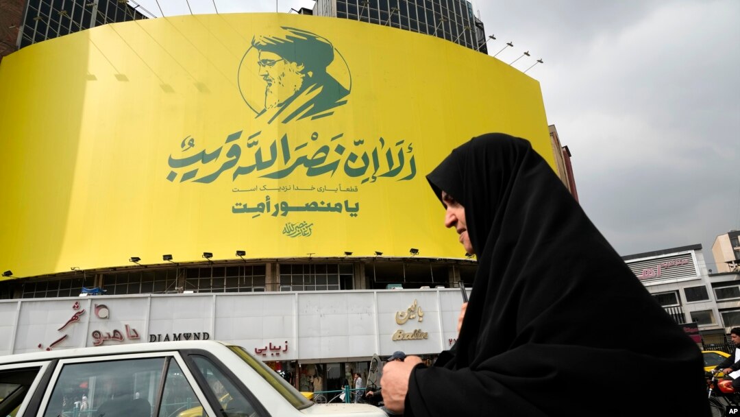 O femeie iraniană trece pe lângă un banner uriaș al liderului ucis al Hezbollah, Hassan Nasrallah, instalat pe o clădire într-o piață din centrul Teheranului, pe 29 septembrie 2024.