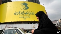 O femeie iraniană trece pe lângă un banner uriaș al liderului ucis al Hezbollah, Hassan Nasrallah, instalat pe o clădire într-o piață din centrul Teheranului, pe 29 septembrie 2024.