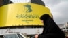 An Iranian woman walks past a huge banner of slain Hezbollah leader Hassan Nasrallah installed on a building at a square in downtown Tehran on Sepember 29.