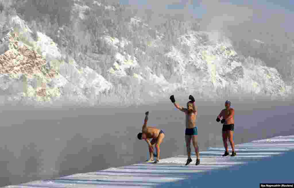 Members of the Dolphin winter swimming club warm up on an embankment of the Yenisei River ahead of their weekly bathing session, with the air temperature at about minus 28 degrees Celsius, in the Siberian town of Divnogorsk. (Reuters/Ilya Naymushin)