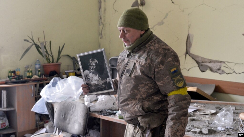 Маж со портрет од Џон Ленон во оштетена зграда во Харков, 1 март 2022