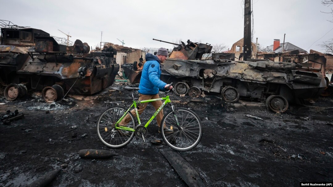Un bărbat suprins în fața unor vehicule militare rusești distruse în localitatea Bucea, în apropiere de capitala Ucrainei, Kiev, marți, 1 martie 2022. Rusia a intensificat marți bombardamentele asupra celui de-al doilea oraș ca mărime al Ucrainei, Harkov, lovind ținte civile. 