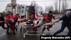 Mentősök viszik hordágyon egy lakónegyed elleni orosz támadás egyik áldozatát Mariupolban 2022. március 1-jén