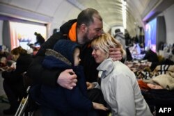 Serhiy Badylevych hugs his wife, Natalya, and child in a Kyiv subway station where they went to seek shelter from shelling earlier this month.