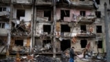 FILE - A man walks past a building damaged following a rocket attack, in Kyiv, Ukraine, Friday, Feb. 25, 2022. The International Criminal Court's prosecutor has put combatants and their commanders on notice that he is monitoring Russia's invasion of Ukra