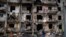 FILE - A man walks past a building damaged following a rocket attack, in Kyiv, Ukraine, Friday, Feb. 25, 2022. The International Criminal Court's prosecutor has put combatants and their commanders on notice that he is monitoring Russia's invasion of Ukra