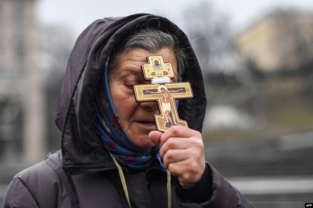 Жена се моли со православен крст на Плоштадот на независноста во Киев, на првиот ден на руската инвазија врз Украина