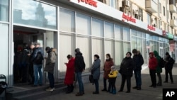 Люди стоят в очереди, чтобы снять деньги в банкомате Альфа-банка в Москве. 27 февраля 2022 года. Россияне устремились к банкам и банкоматам вскоре после того, как Россия начала атаку на Украину, а Запад объявил суровые санкции