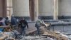 People remove debris on March 1 outside the regional administration building in Kharkiv, which city officials said was hit by a missile attack.