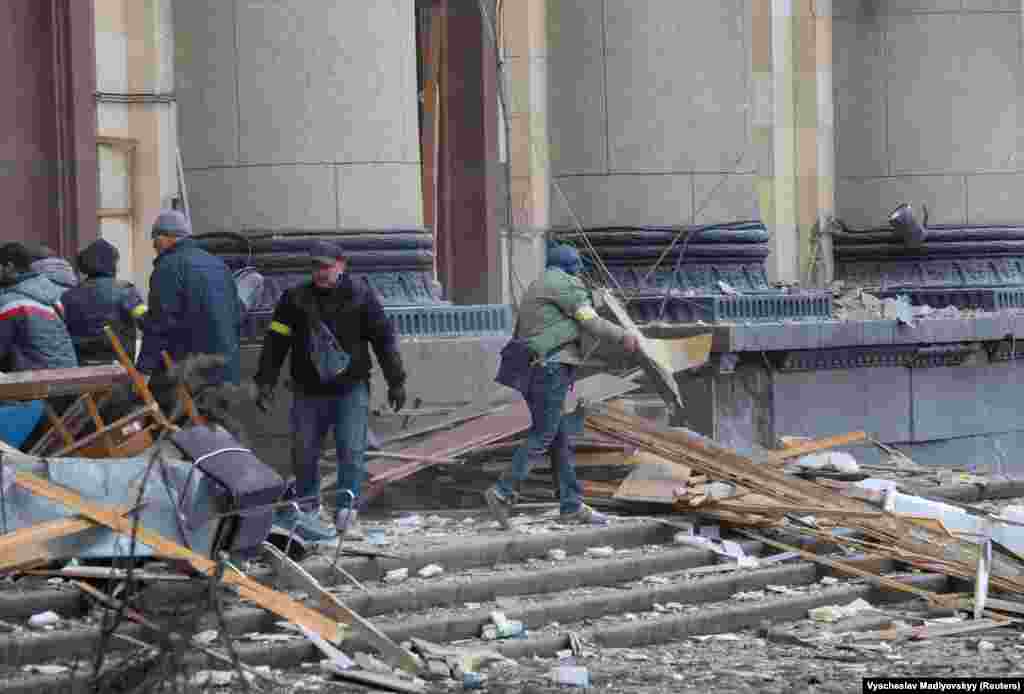 People remove debris on March 1 outside the regional administration building in Kharkiv, which city officials said was hit by a missile attack.
