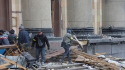 Građani čiste ispred administrativne zgrade u centru Harkova nakon granatiranja, 1. mart 2022.
