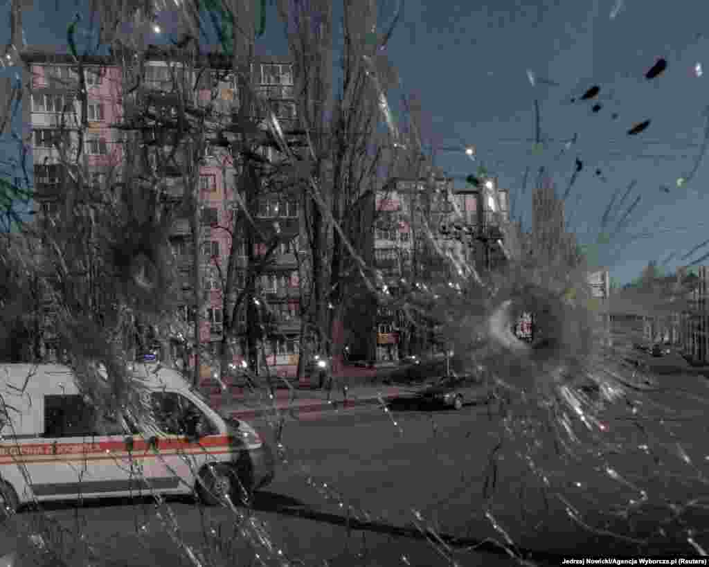 An ambulance is seen through the damaged window of a vehicle hit by bullets in Kyiv on February 28.
