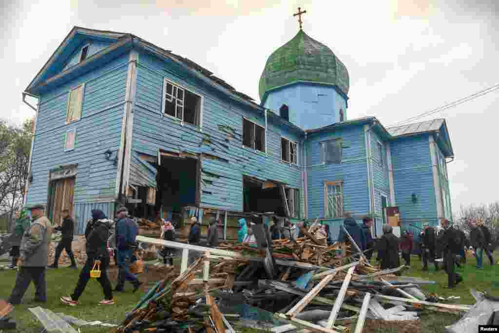 Local residents walk after the Orthodox Easter service next to the Nativity of the Holy Virgin Church, which was damaged by shelling, in the village of Peremoha, in the Kyiv region.