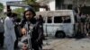 Pakistani police inspect the site around a damaged vehicle following a suicide attack near the Confucius Institute inside Karachi University.